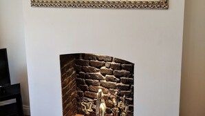 Una habitación con un espejo grande y ornamentado, un cuadro de cebra, una araña y una chimenea de piedra con estatuas.