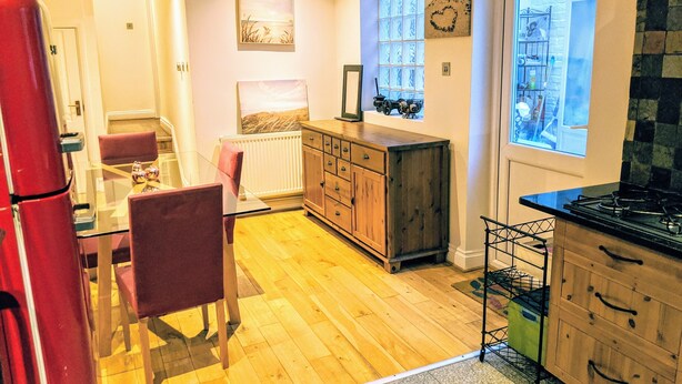 Una cocina con armarios de madera, una mesa de comedor con sillas, un refrigerador y un ventanal con vistas.
