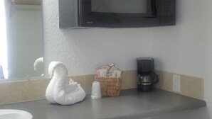 Une cuisine compacte équipée d’un four à micro-ondes, d’une machine à café et d’un petit réfrigérateur.