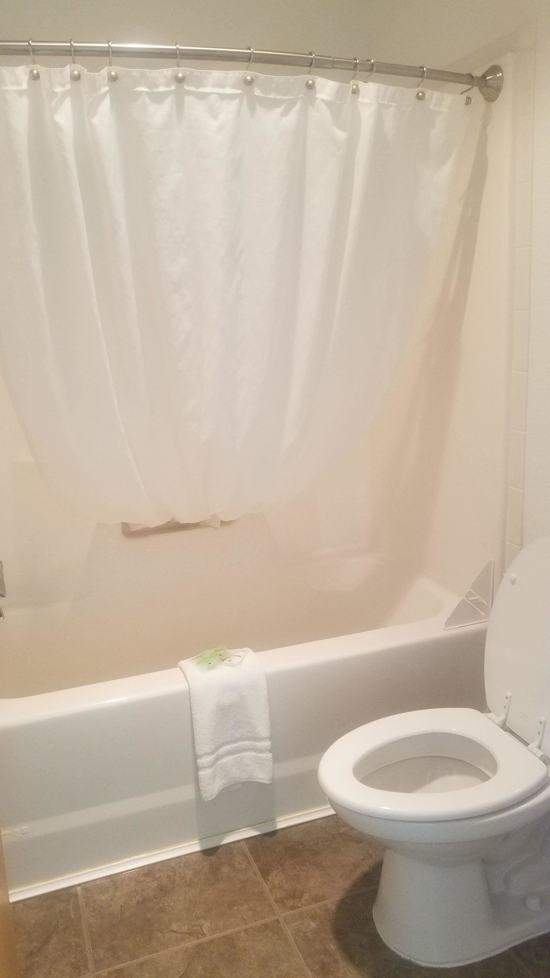 A bathroom with a bathtub, toilet, and a shower curtain.