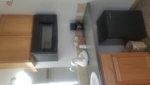 Une cuisine avec des meubles de rangement en bois, un four à micro-ondes, un réfrigérateur noir et un évier.