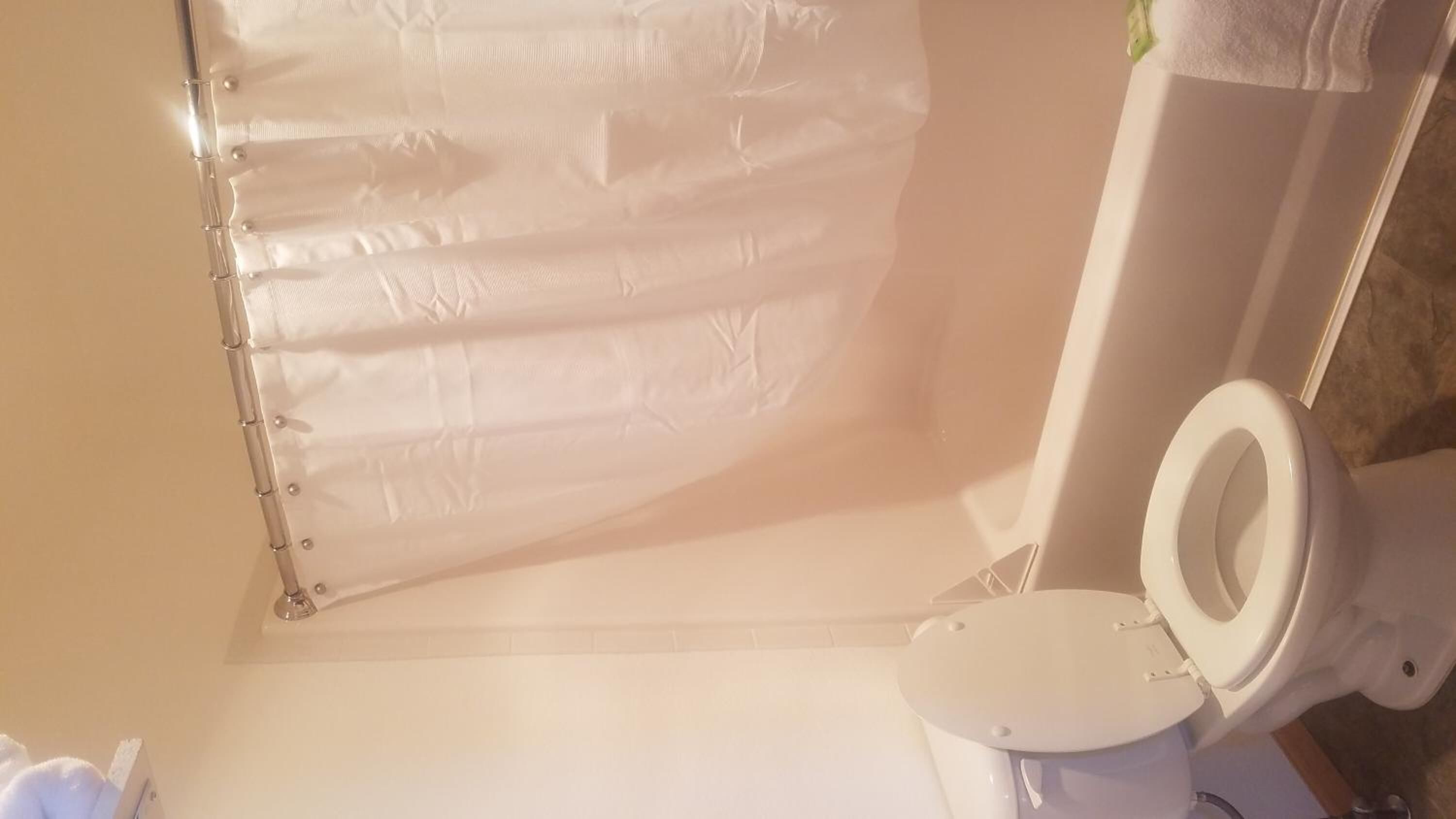 A bathroom with a toilet, a shower curtain, and a tiled floor.