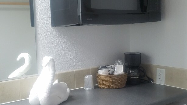 Une cuisine compacte équipée d’un four à micro-ondes, d’une machine à café, d’un évier et d’une poubelle.