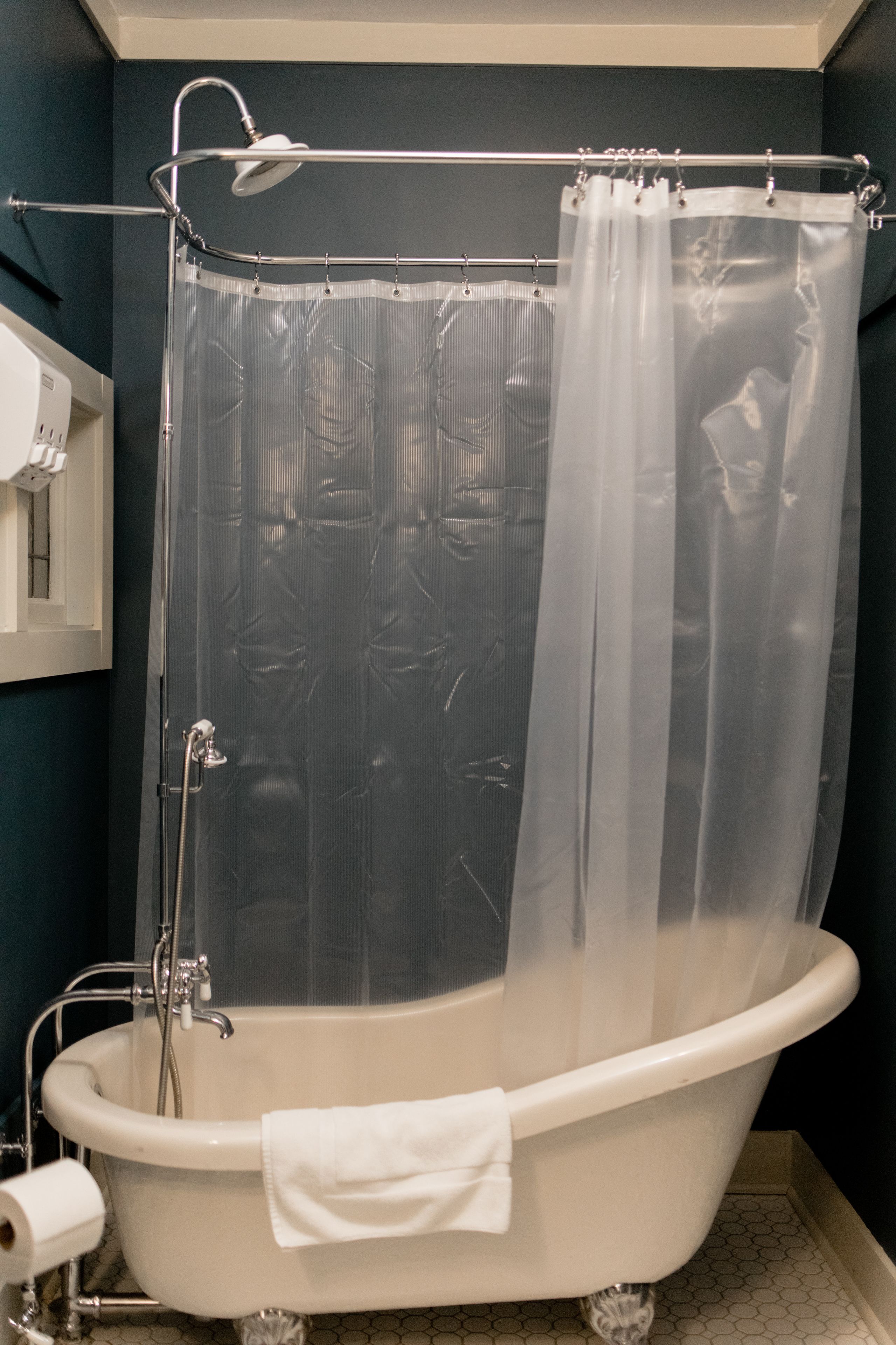 A bathroom with a clawfoot bathtub, a shower curtain, and a towel rack.