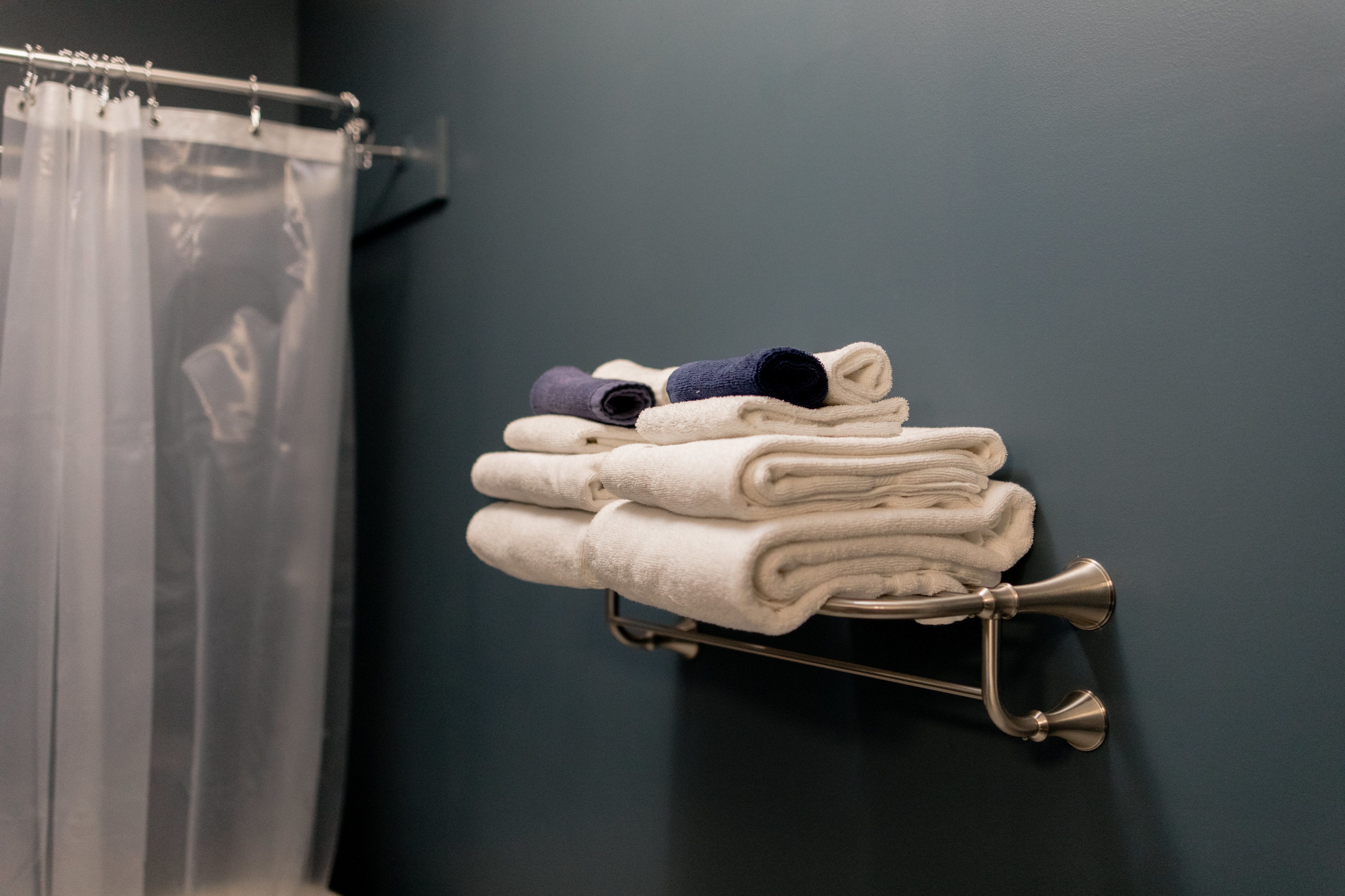 A stack of folded towels on a metal towel rack against a dark wall.