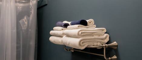 A stack of folded towels on a metal towel rack against a dark wall.