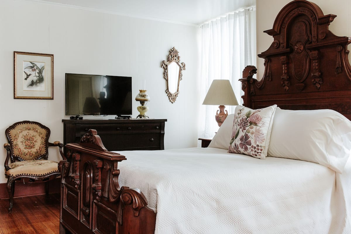 Une chambre à coucher avec un grand lit, une télévision, une commode et une chaise.