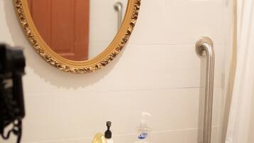 A bathroom with a white sink, gold faucets, a gold-framed mirror, a door, and a grab bar.