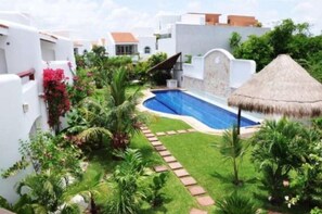 A pool surrounded by lush greenery and white buildings with red accents.