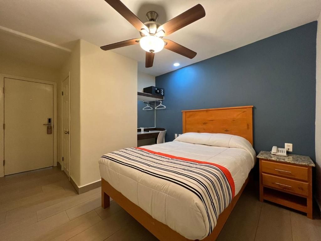 A bedroom with a bed, a wooden headboard, a nightstand, a ceiling fan, and a door.
