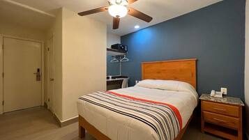 A bedroom with a bed, a wooden headboard, a nightstand, a ceiling fan, and a door.