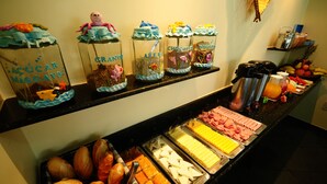 A buffet with various food items and decorative containers. - Pousada Gênesis (Arraial do Cabo)