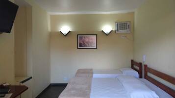 Habitación de hotel con dos camas, un escritorio con silla, televisor y lámparas de pared.
