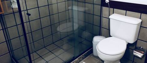A bathroom with a glass-enclosed shower, a white toilet, and a bidet.