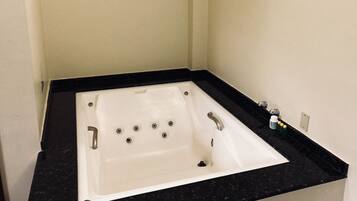 Une salle de bain avec une baignoire blanche, un comptoir noir et un seul robinet.