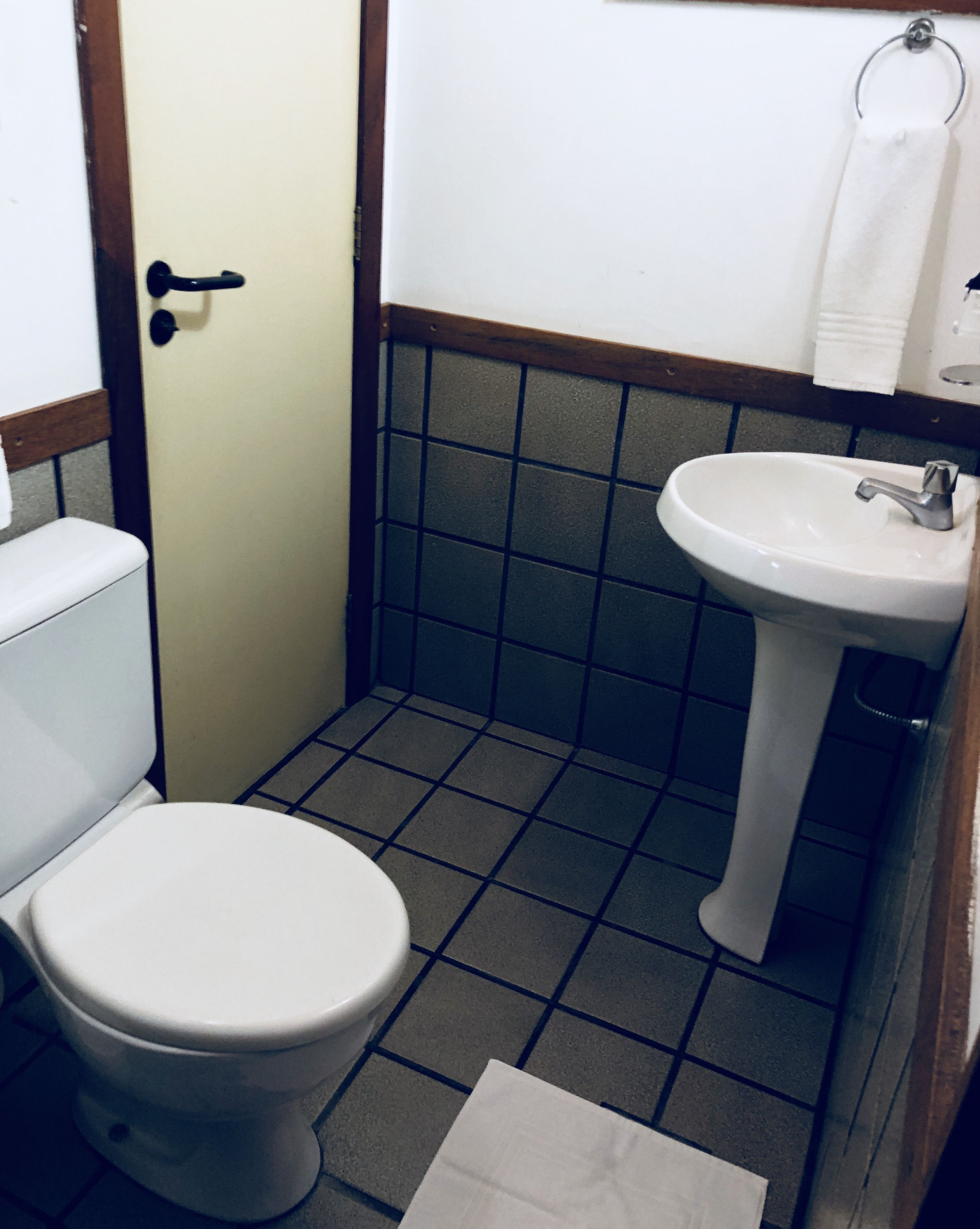 A small bathroom with a toilet, sink, and tiled walls.