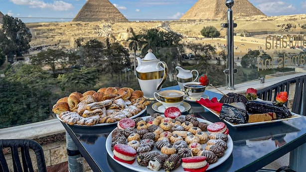 A table with pastries and a teapot overlooking the pyramids.