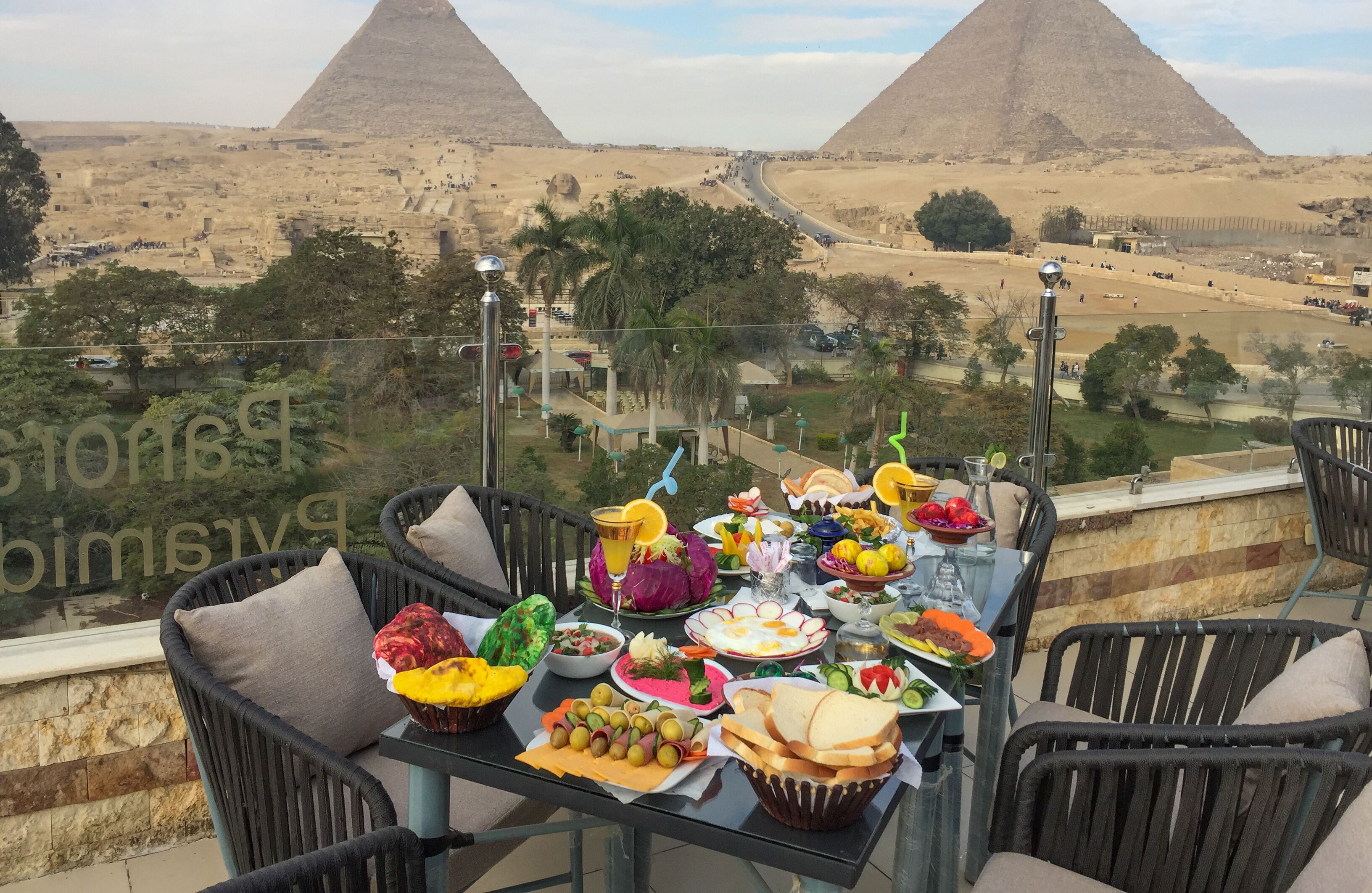 A table set with various dishes and a view of pyramids in the background.