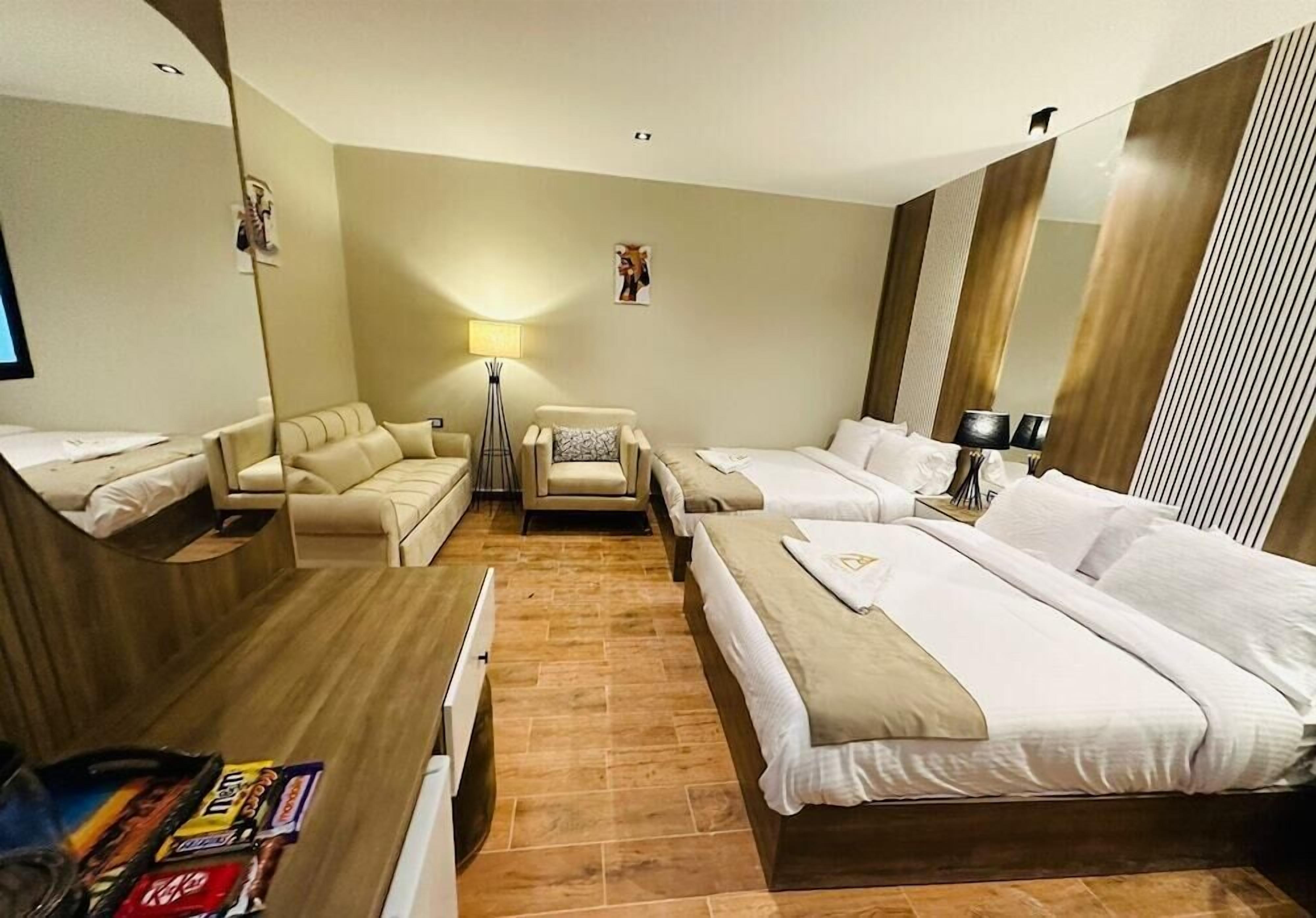 Habitació d'hotel amb dos llits, un sofà, una taula i un mirall.
