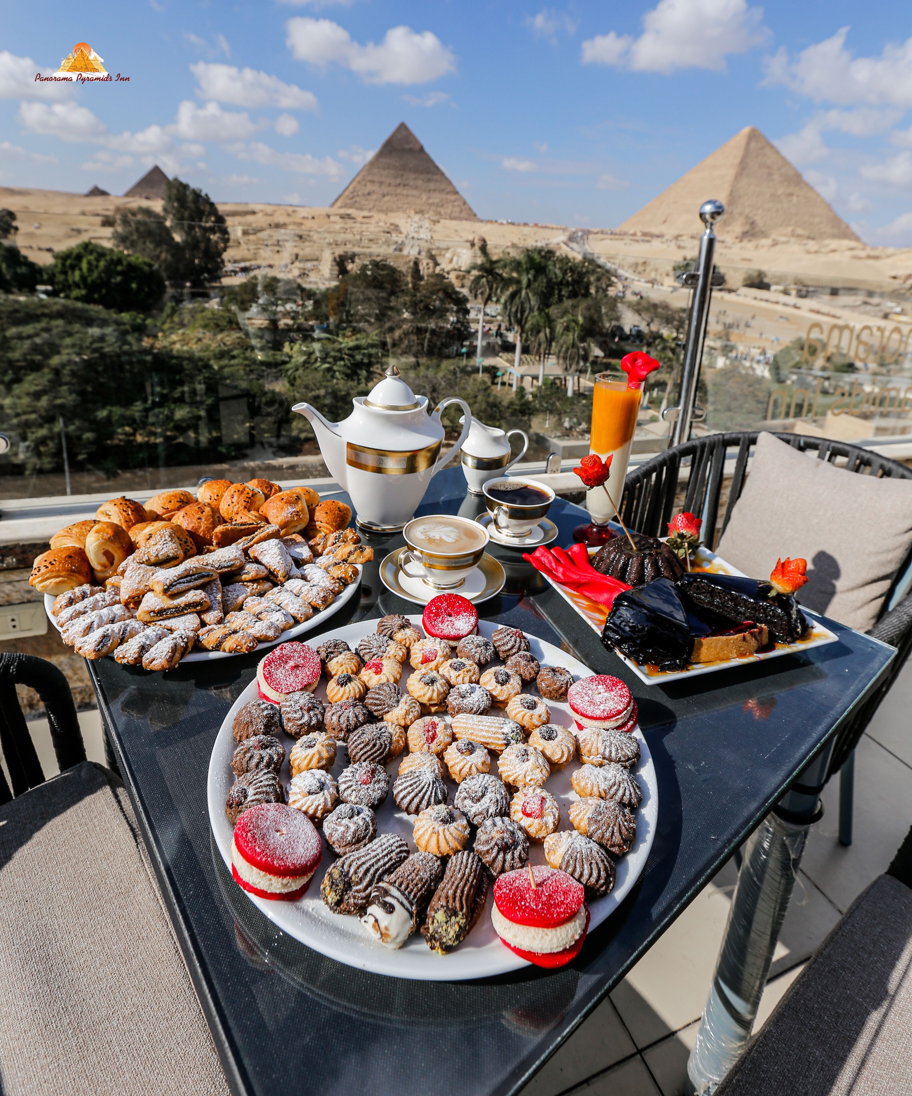 A table set with pastries, coffee, and a view of pyramids.