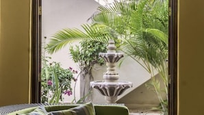 A room with a green sofa and a view of a courtyard featuring a fountain and palm trees. - FN118-Loreto Bay-Artistic Cozy Villa (Loreto)