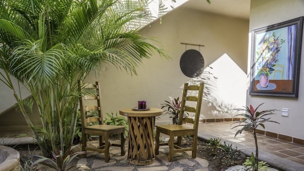 A patio area with a round table and four wooden chairs, surrounded by potted plants and a small garden. - FN118-Loreto Bay-Artistic Cozy Villa (Loreto)