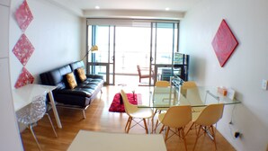 Una sala moderna con sofá, una mesa de vidrio, sillas y televisor.