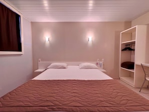 A bedroom with a bed, two bedside lamps, a wardrobe, and a window with curtains. - Igaras hotel (Otacilio Costa)