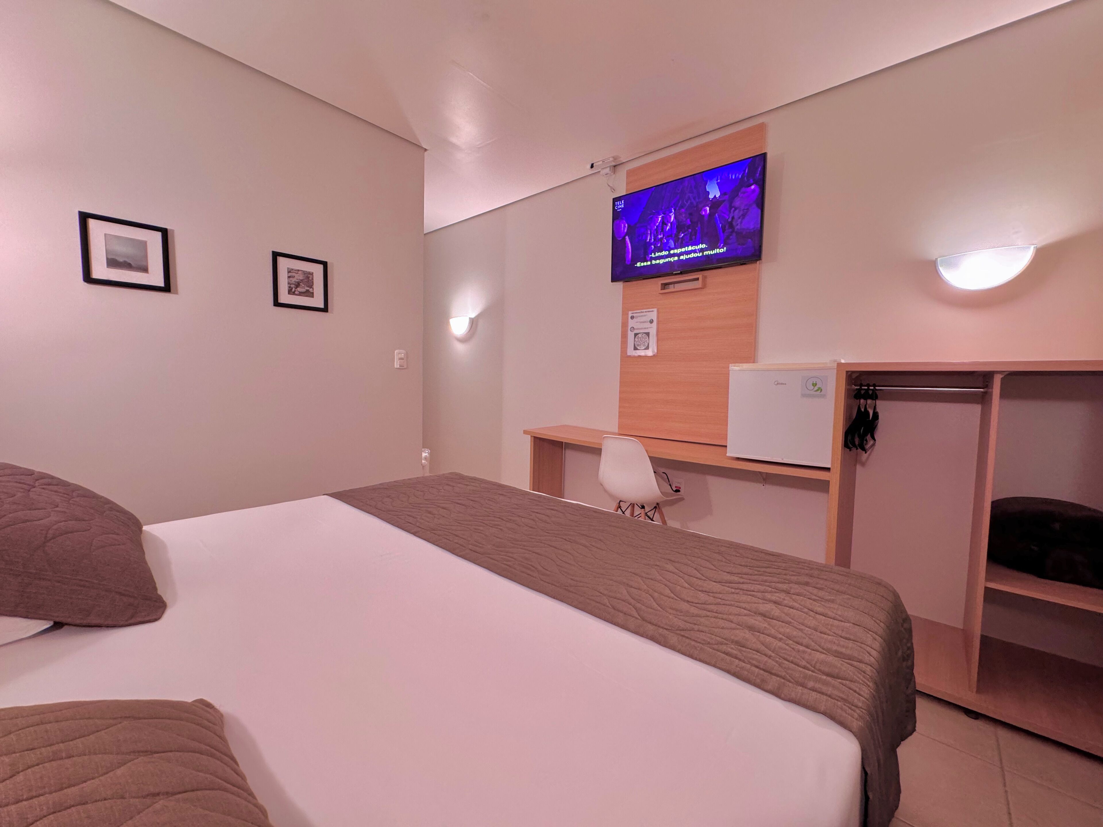 A hotel room with a bed, a desk, a television, and a wardrobe.