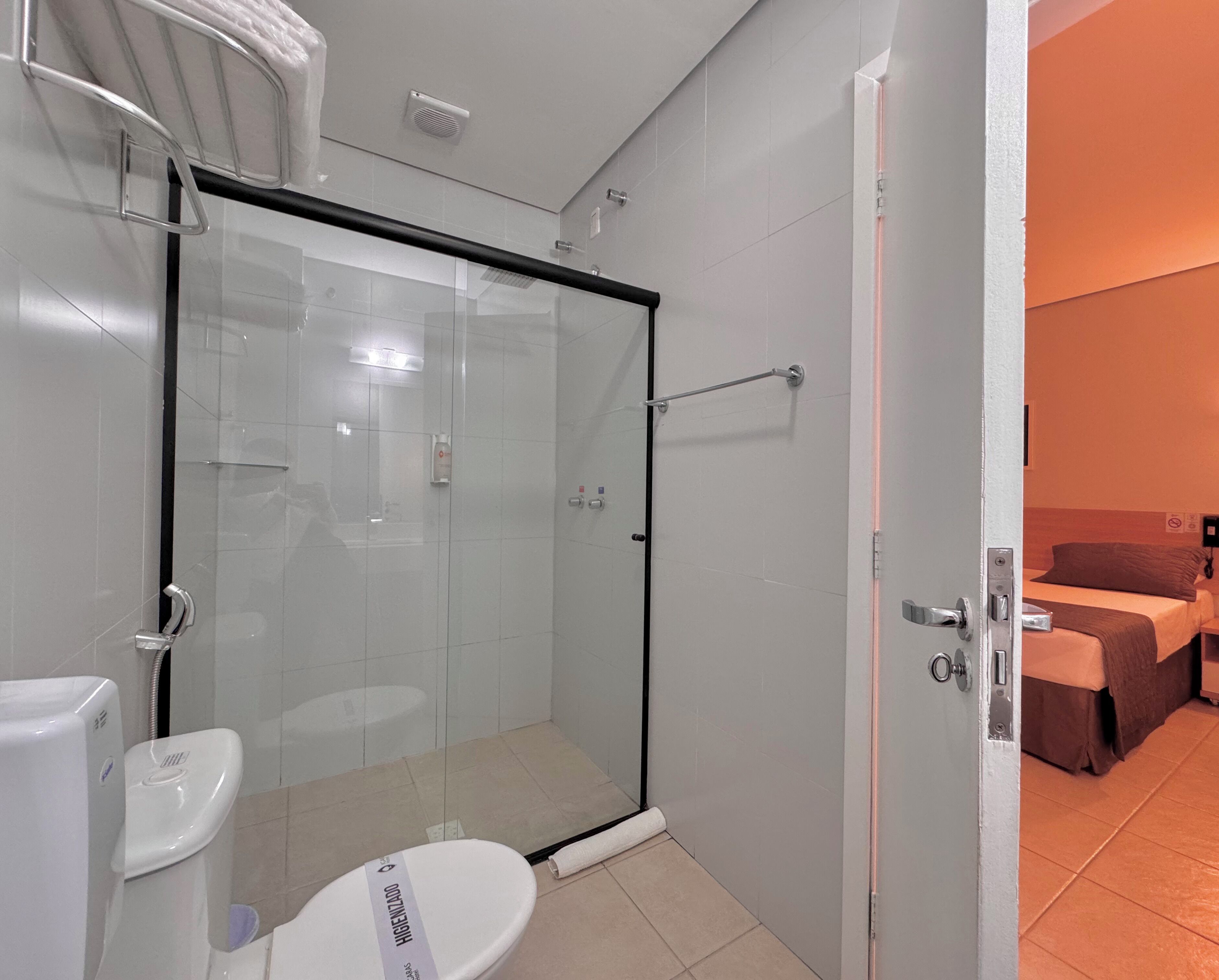 A modern bathroom with a glass shower enclosure, a toilet, and a visible towel rack.