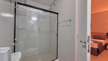 A modern bathroom with a glass shower enclosure, a toilet, and a visible towel rack.