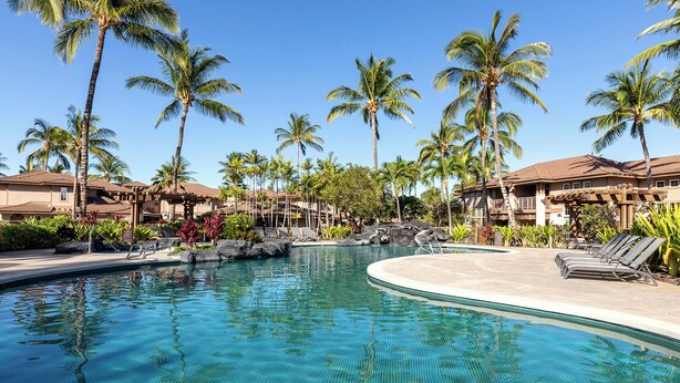 A resort pool area with clear blue water, palm trees, and a building with a brown roof. - Walk to Golf 250' from your door. Swim, Play, Feel the Warmth of Caring Owner (Waikoloa)