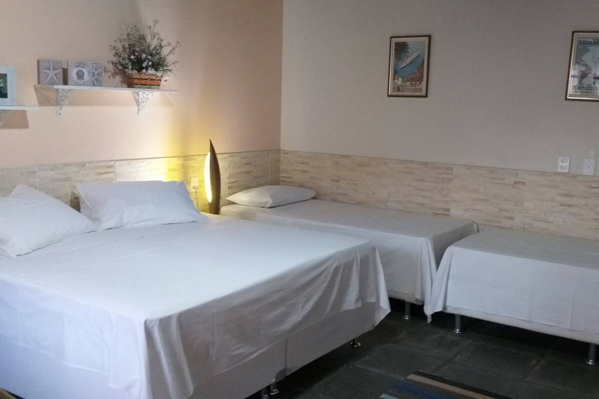 Habitación de hotel con dos camas individuales, una mesita pequeña, una silla y una estantería de pared con adornos.