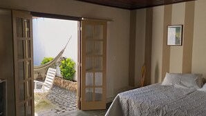 A bedroom with a bed, a television, a hammock, and a view of the outdoors. - Casa das Orquídeas (Arraial do Cabo)