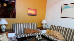 A living room with two striped sofas, a glass coffee table, and two lamps. - Casa das Orquídeas (Arraial do Cabo)