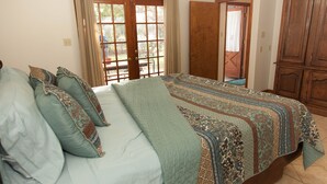 Una camera da letto con un letto, cuscini, una finestra e una porta.