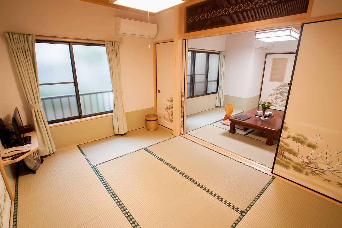 A traditional Japanese room with tatami flooring, sliding doors, and a view of a balcony.