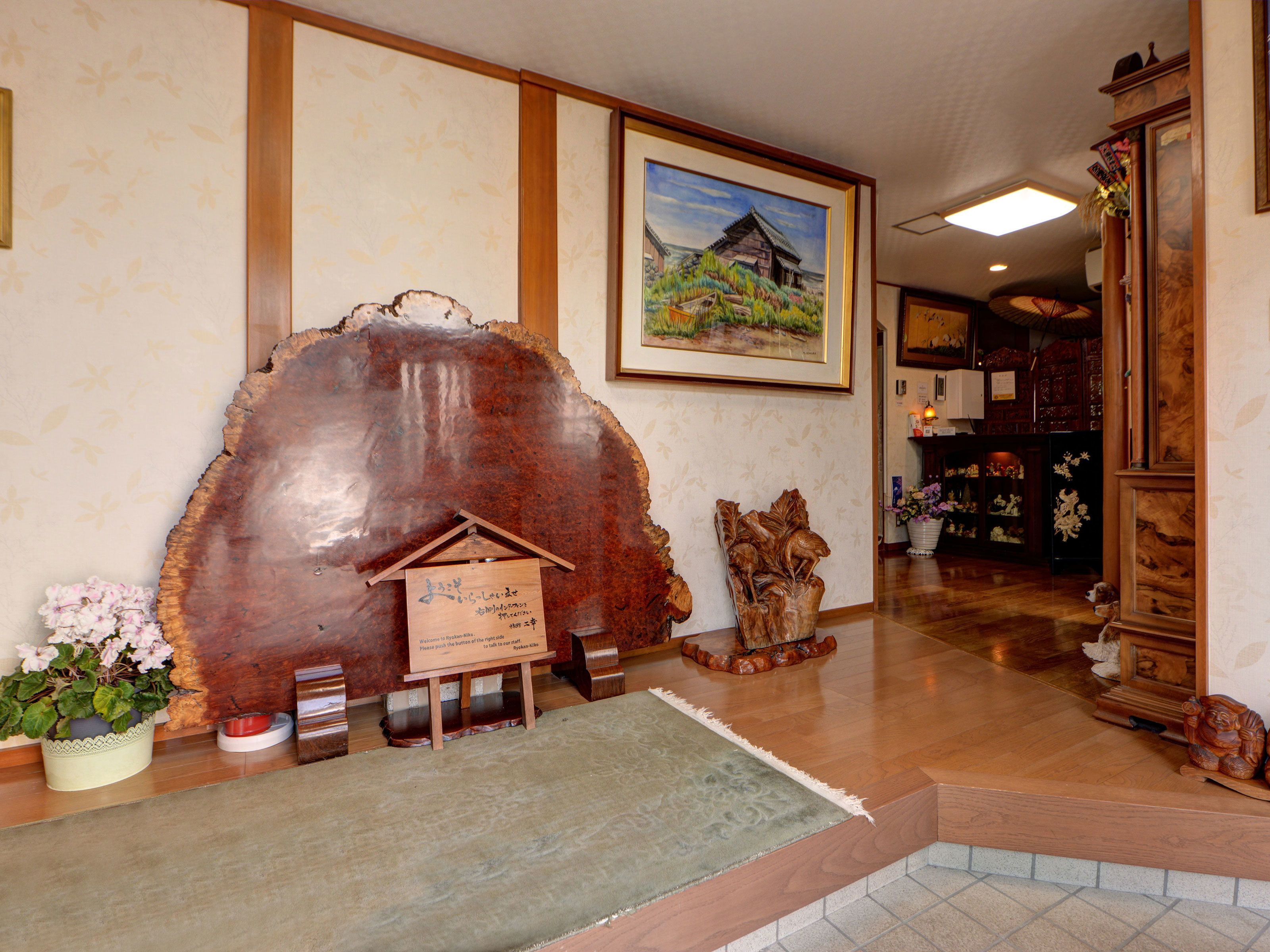 A reception area with a wooden sculpture, a framed painting, and a welcome sign.