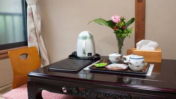 A wooden desk with a tea set, a vase with flowers, and a tissue box.