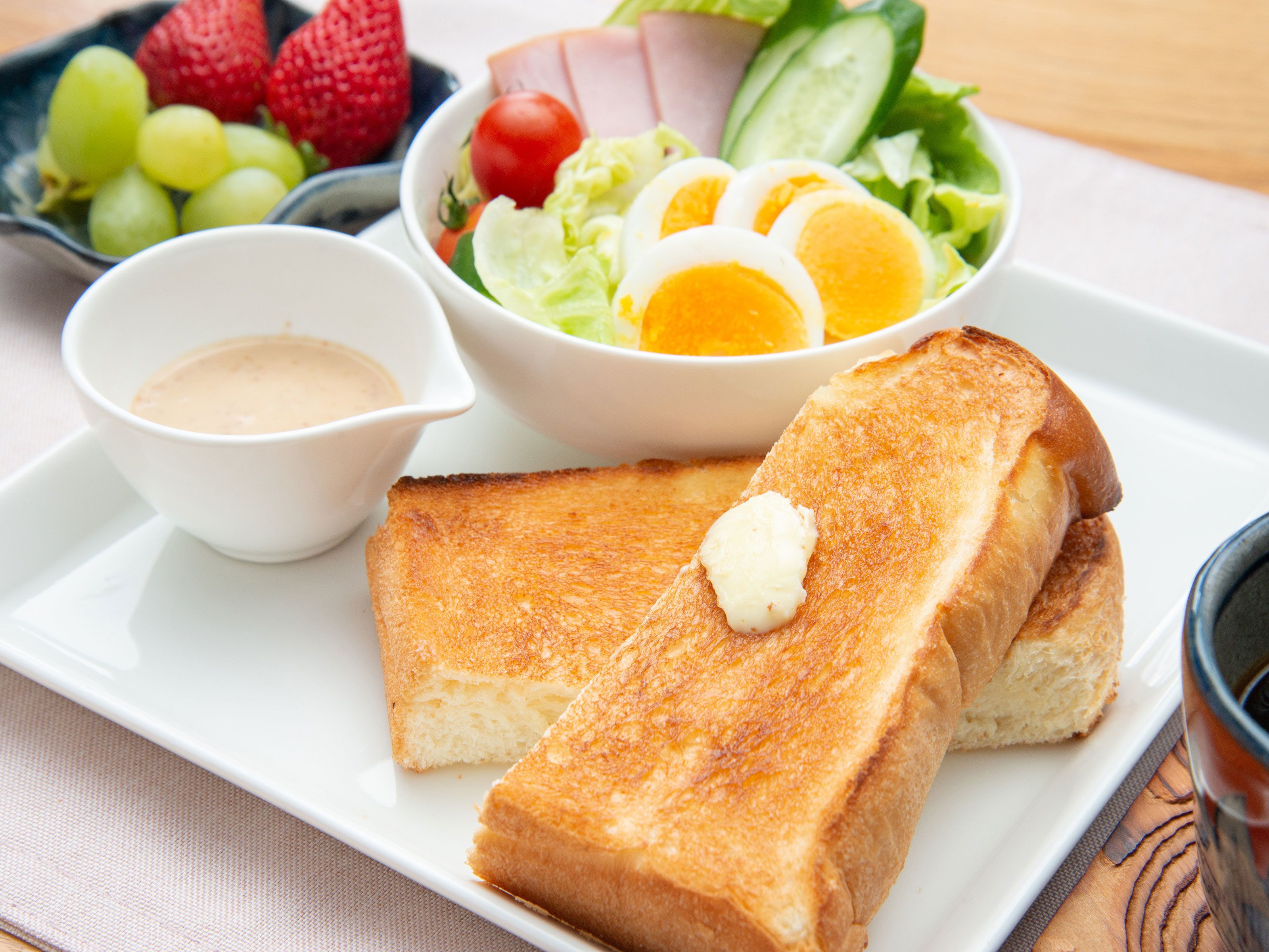 A plate with toasted bread, a salad, and a small bowl of sauce.
