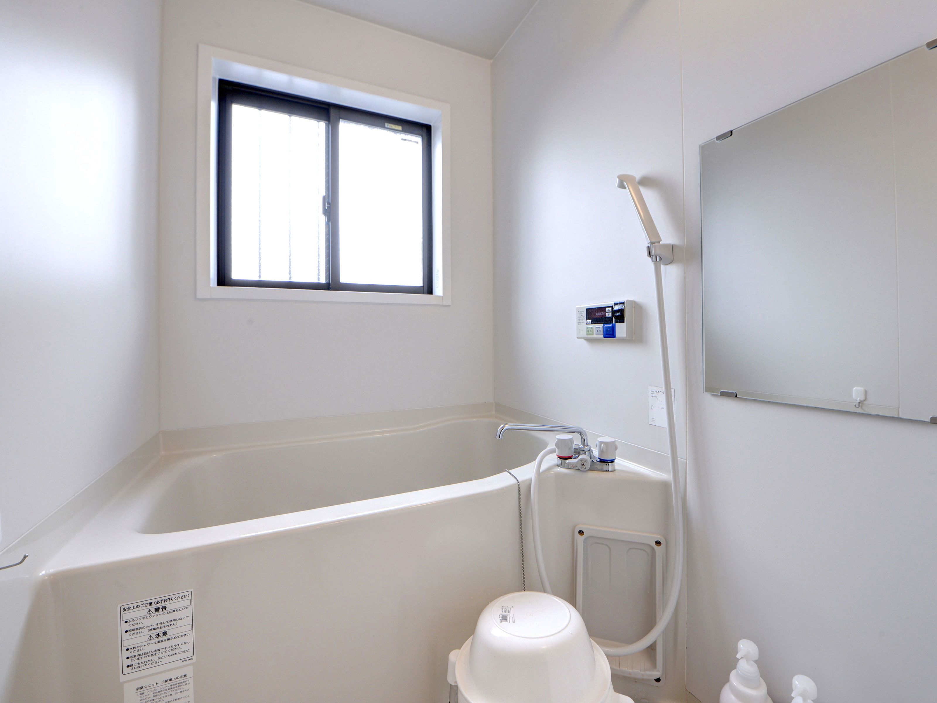 A bathroom with a bathtub, a window, a shower, and a toilet.