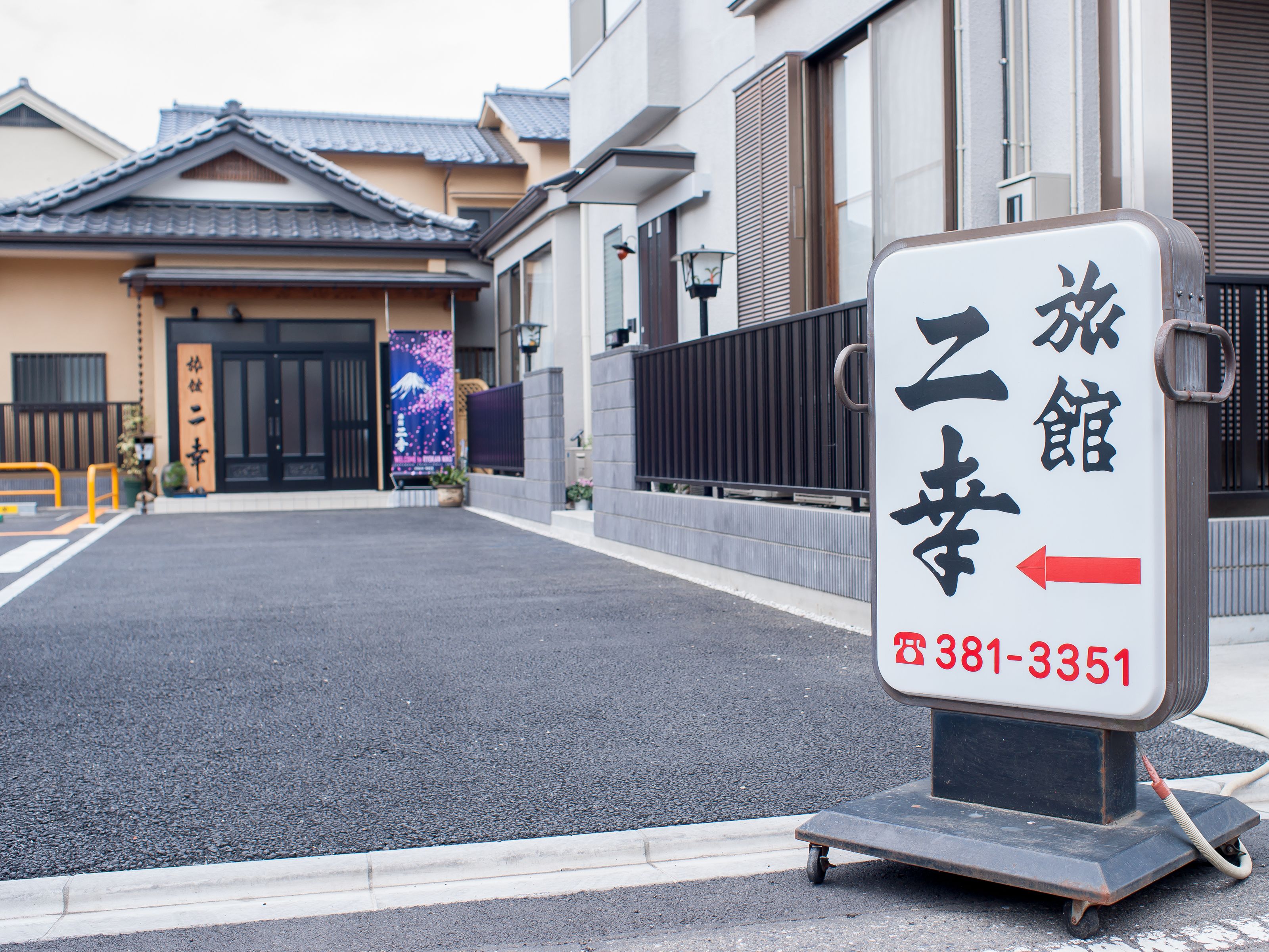 Een bord van een hotel met Japanse karakters en een telefoonnummer.