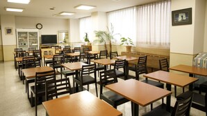 A dining area with multiple tables and chairs, a television, and a clock on the wall. - Koga Central Hotel (Koga)