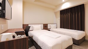 A hotel room with two beds, a desk, a chair, a coffee maker, and a TV.
