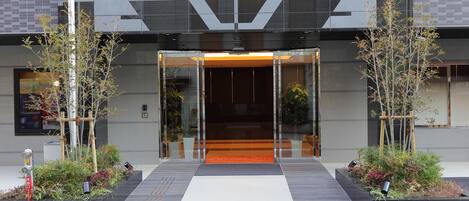 A modern building entrance with glass doors, a ramp, and potted plants.