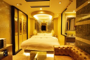 A hotel room with a large bed, a sitting area, a television, and a bathroom with a sink and mirror. - Hotel Granhill - Adults Only (Tokyo)