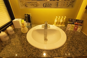 A hotel bathroom with a granite countertop, a white sink, and toiletries. - Hotel Granhill - Adults Only (Tokyo)