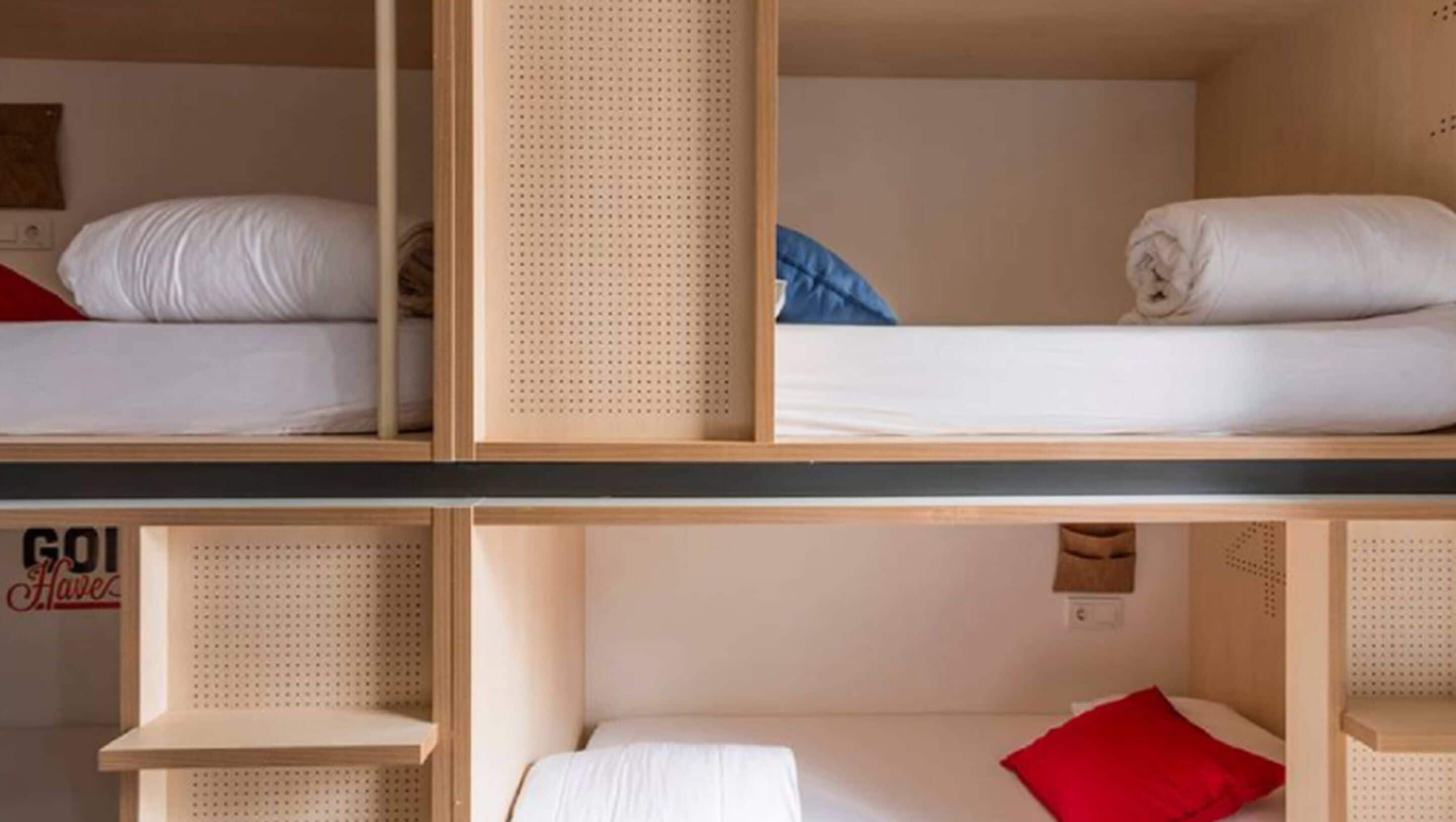 Ett rum i studentkorridorsstil med våningssängar, hyllor i trä och en skylt på väggen.