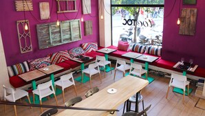 A restaurant interior with red and white seating, wooden decor, and large windows. - TOC Hostel Sevilla (Seville)