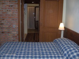 Una habitación con una cama, una puerta de madera y una lámpara.